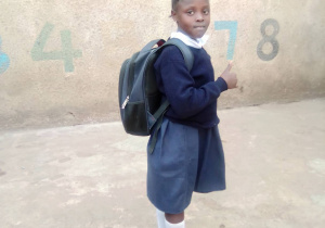 Zdjecie przedstawia kenińskie dziecko w mundurku z plecakiem szkolnym